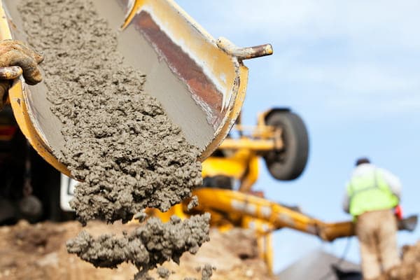 Close-up view of wet concrete at the end of the chute of a cement mixer.