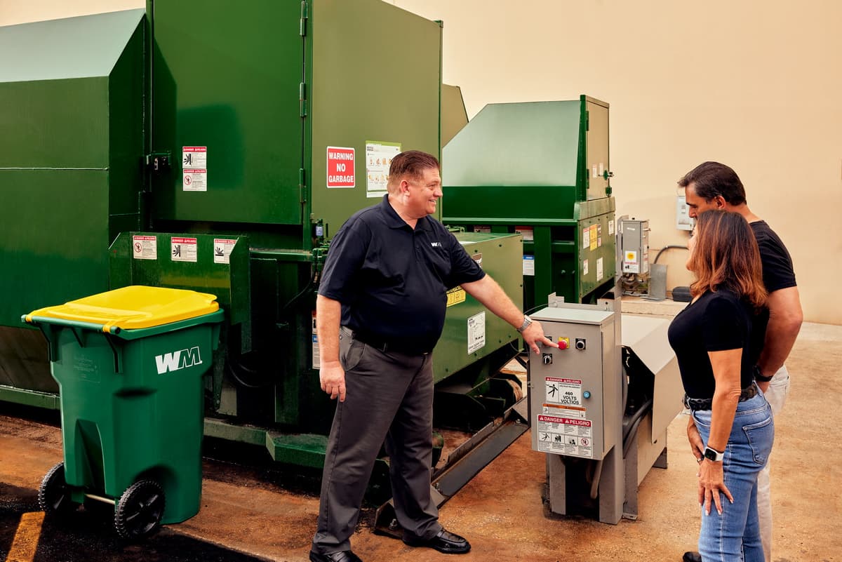 A WM representative trains customers on how to use a commercial compactor.