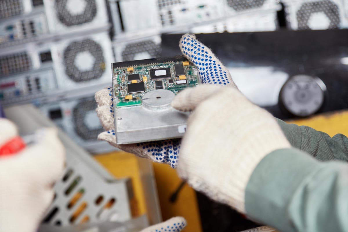 A component of a computer is held in a person's gloved hands.