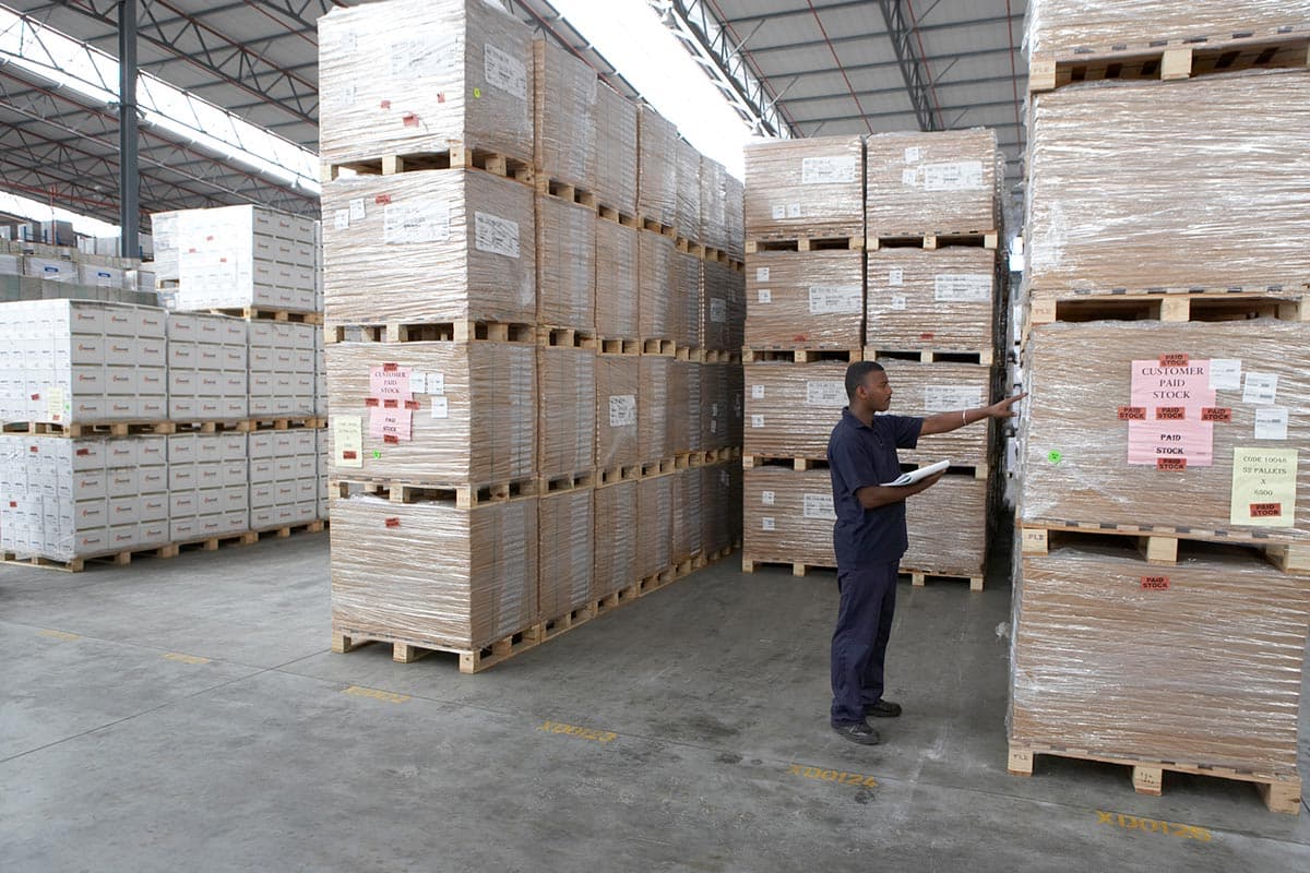Employee looks at items in a warehouse stored on pallets.