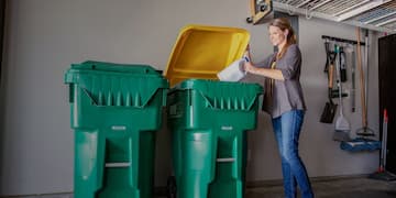 Woman deposits plastic jug in a WM recycling cart